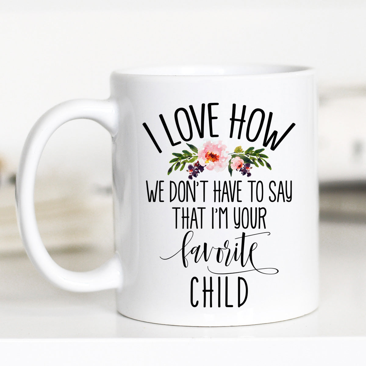 11 ounce white mug. Floral with text "i love how we don't have to say i'm your favorite child"