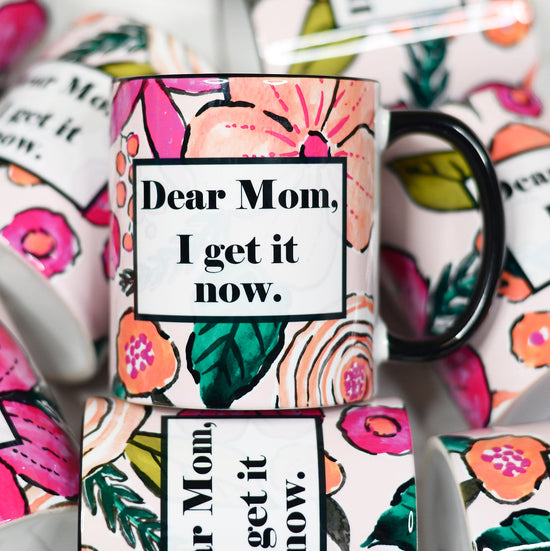 11 ounce mug black hand and rim. Floral design all over with box of text "Dear mom, I get it now"