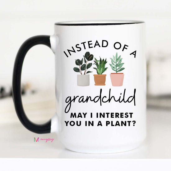 15 oz mug. Black handle and rim. Plants with text "instead of a grandchild may i interest you in a plant"