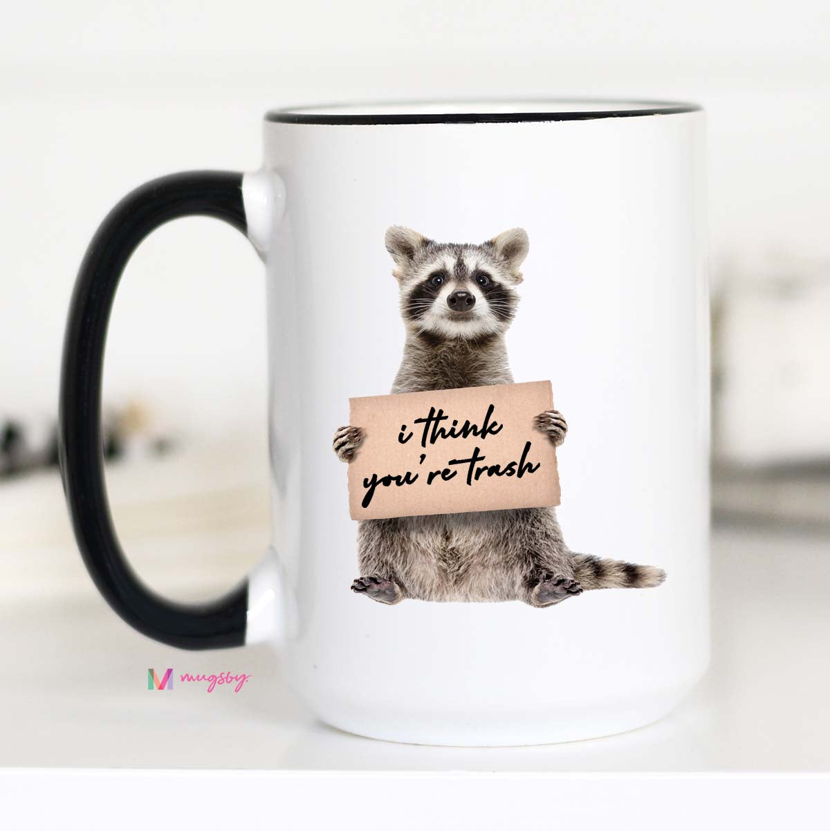 15 oz mug. Black handle and rim. Image of a raccoon holding a sign "i think you're trash"