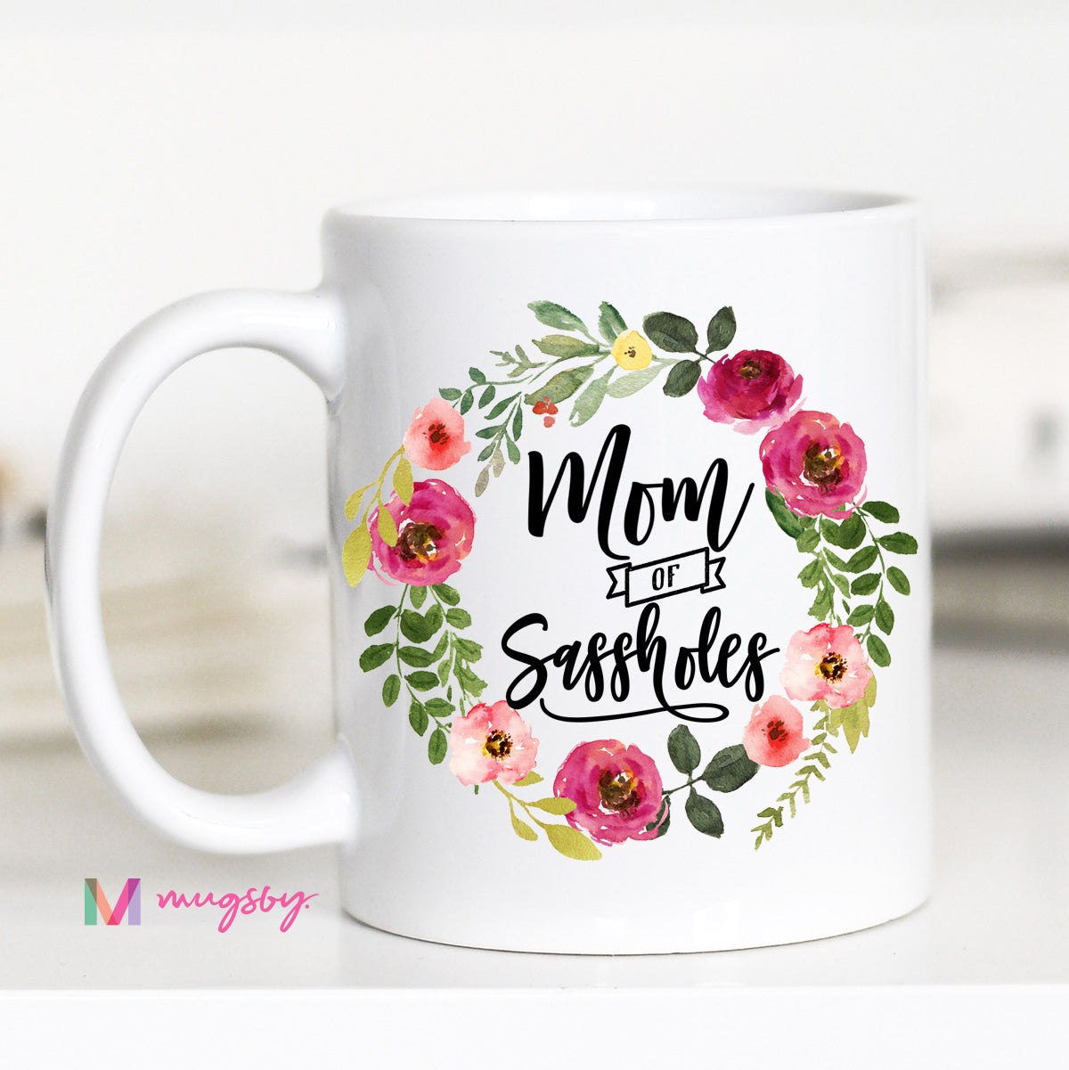 11 ounce white mug. Floral wreath with text "mom of sassholes"