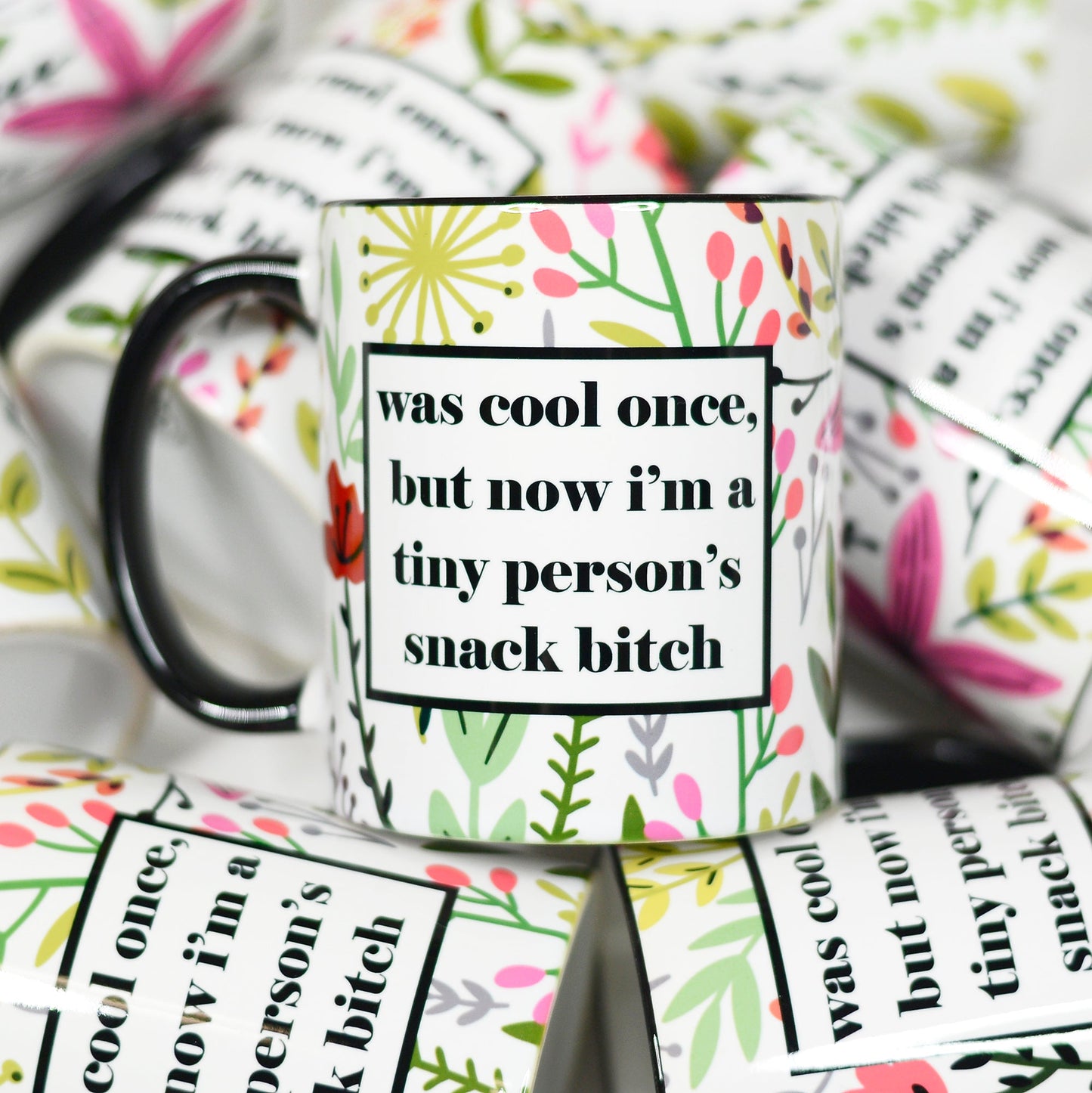 11 ounce mug black hand and rim. Floral pattern all over. Box with text "Was cool once, but now I'm a tiny person's snack bitch"